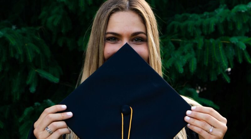 college student holds graduation cap in front of her face